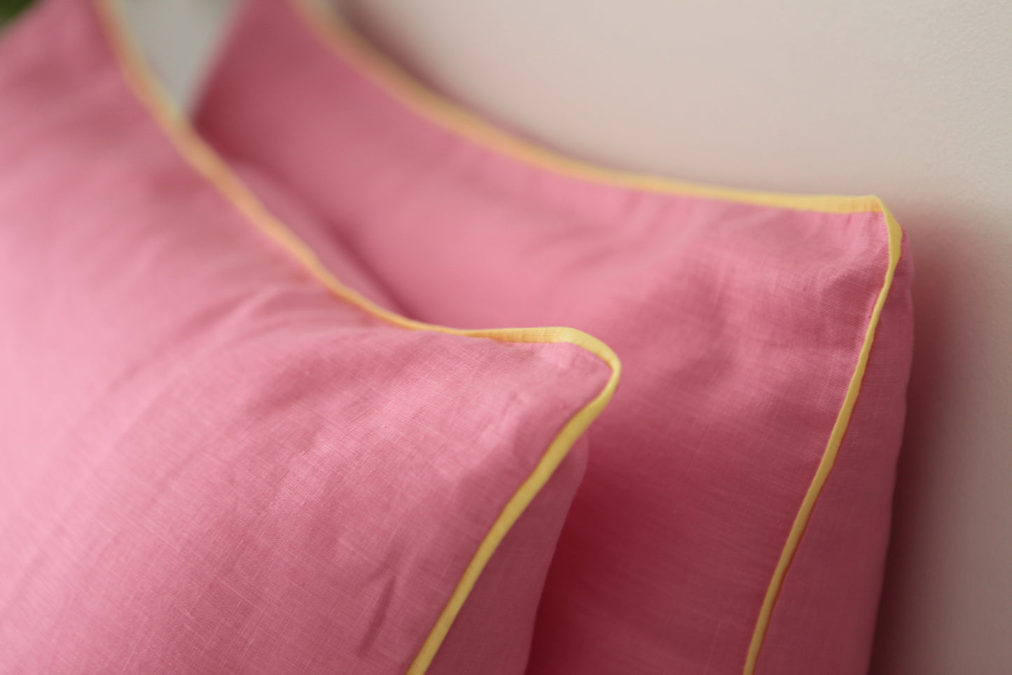 Baby pink linen pillowcases with lemon linen piping. Close up image on 45 degree angle.