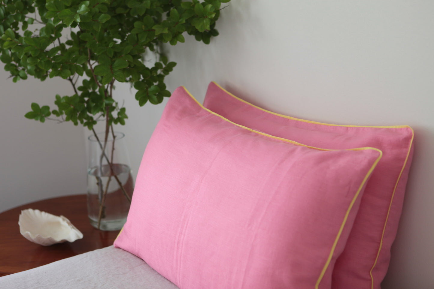 Baby pink linen pillowcases with lemon linen piping. Studio shot.