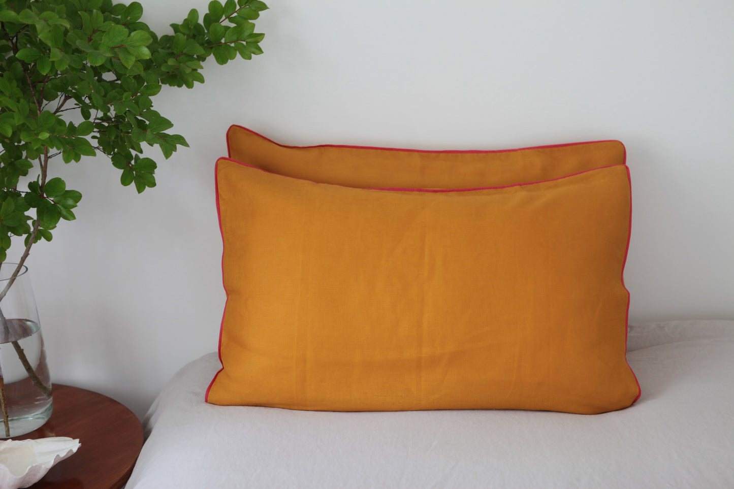 Burnt orange linen pillowcases with magenta linen piping. Front on photo.