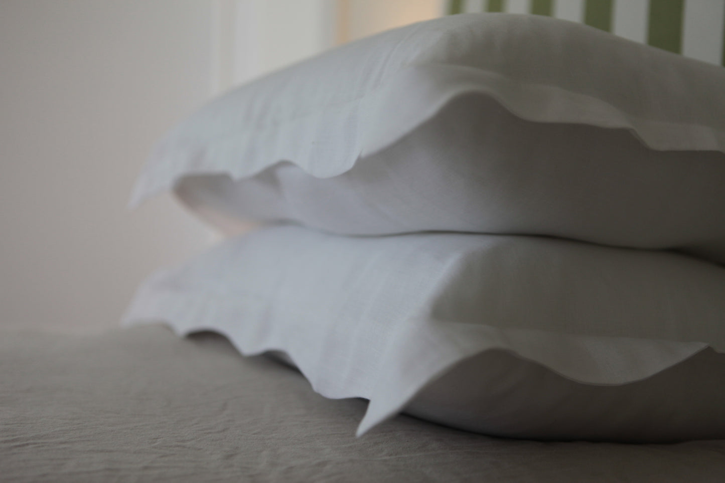 Out of focus image of white linen pillowcases with organic wave edge.
