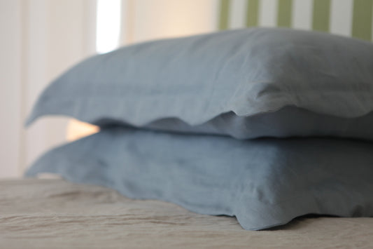 Sky blue linen pillowcases with organic wave border edge. Photo from corner angle. 