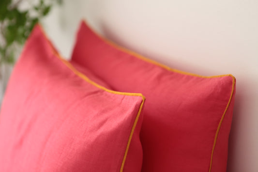 Magenta linen pillowcases with burnt orange piping. 45 degrees angle photo. 