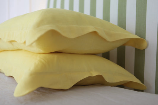 Lemon linen pillowcases stacked. 45 degree angle photo. Organic wave edge border.