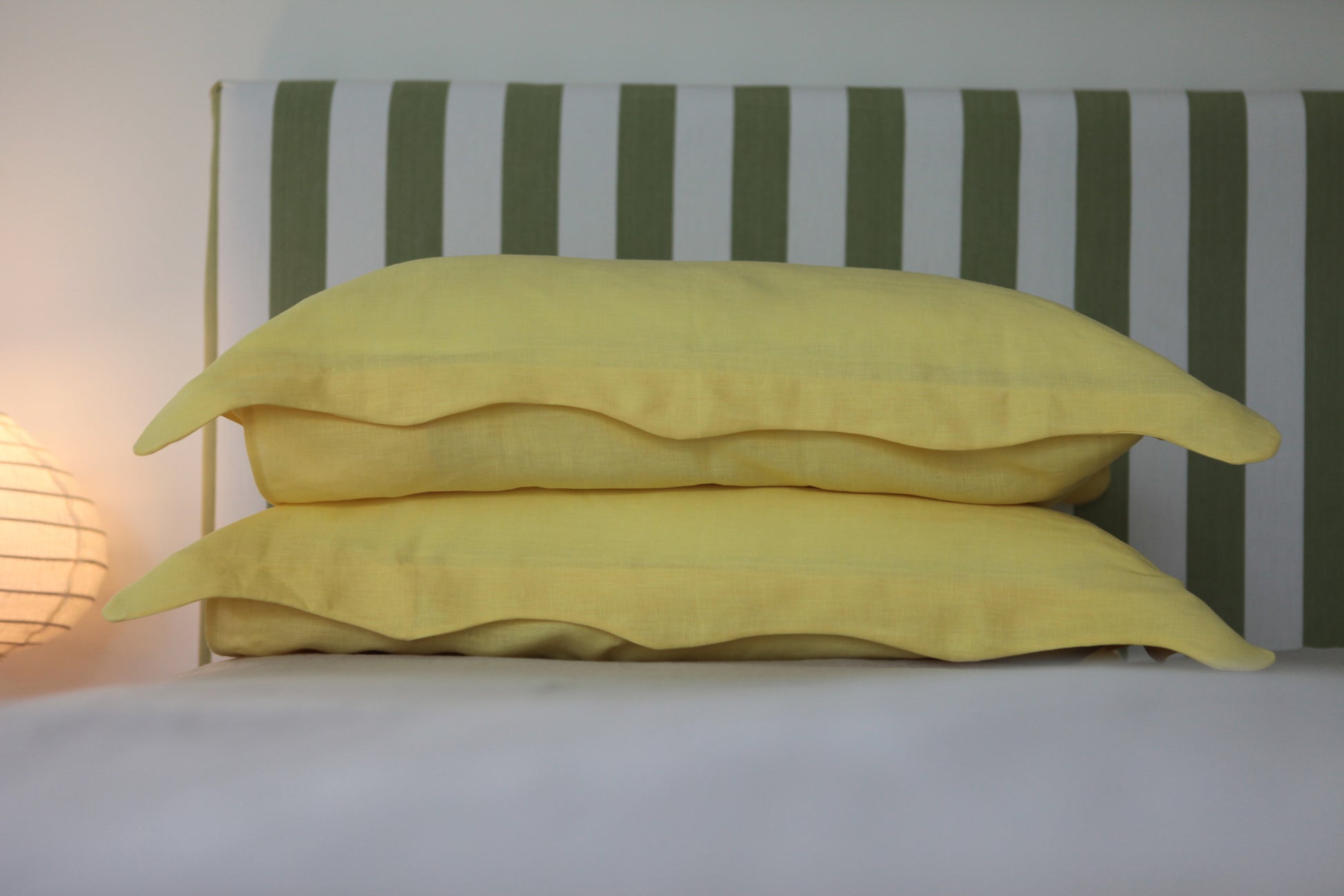 Lemon coloured linen pillow cases with organic wave edge border. Stacked, front on photo. 
