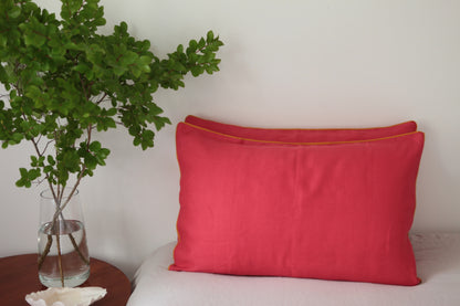 Magenta linen pillowcases with burnt orange linen piping. Front on photo.