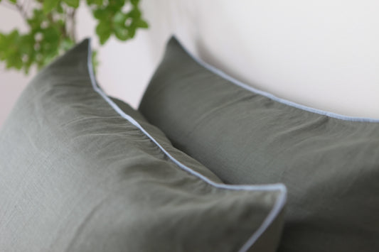 Khaki linen pillowcases with sky blue linen piping. Close up photo. 