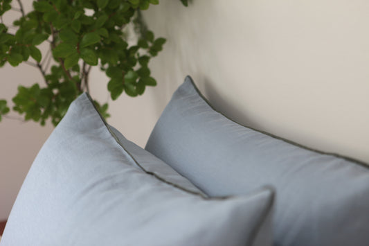 Sky blue linen pillowcases with khaki linen piping. Close up photo of piping. 