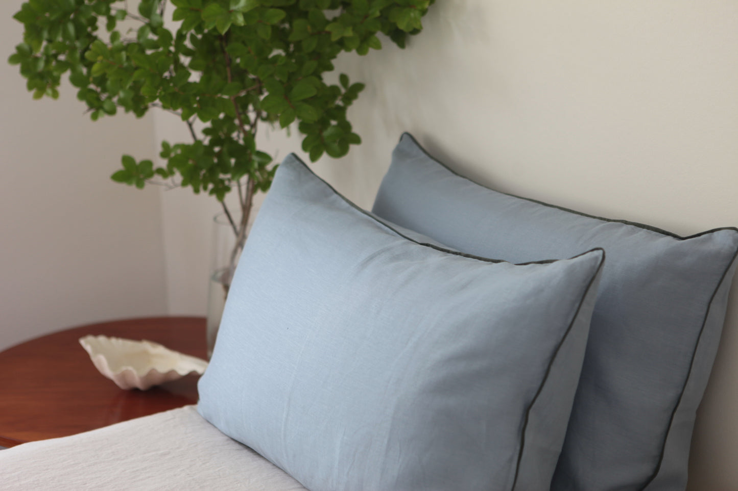Sky blue linen pillowcases with khaki linen piping. Side photo. 