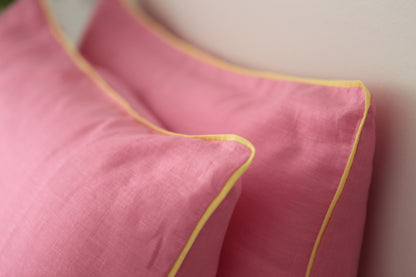 Baby pink linen pillowcases with lemon linen piping. Close up image on 45 degree angle. 