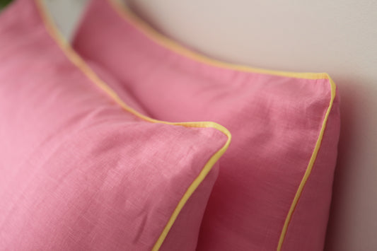 Baby pink linen pillowcases with lemon linen piping. Close up image on 45 degree angle. 