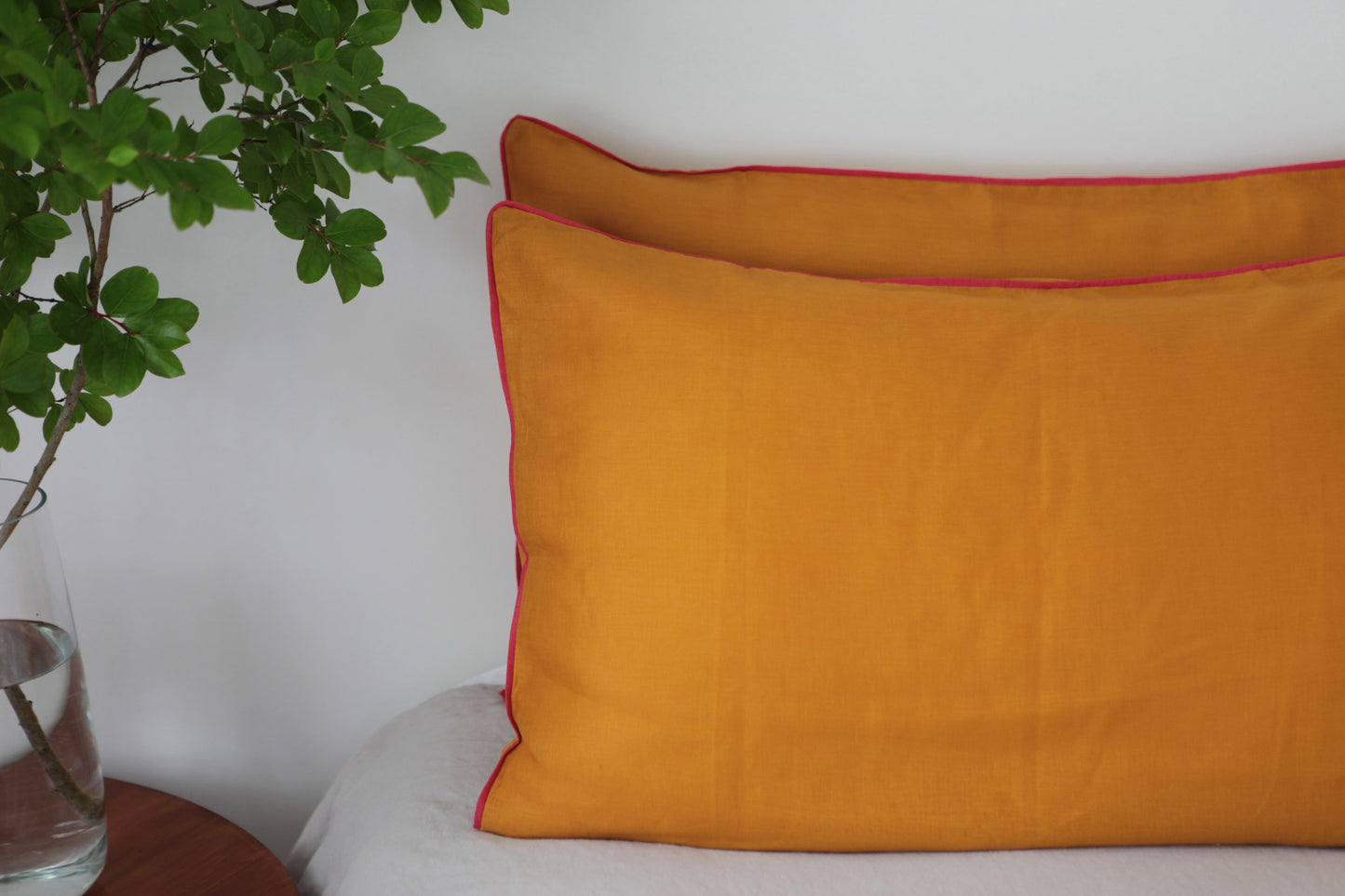 Burnt orange linen pillowcases with magenta linen piping. Half photo. 