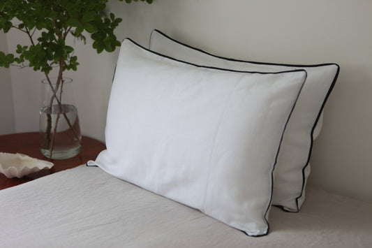 White linen pillowcases with navy linen piping. Wide angle photo. 