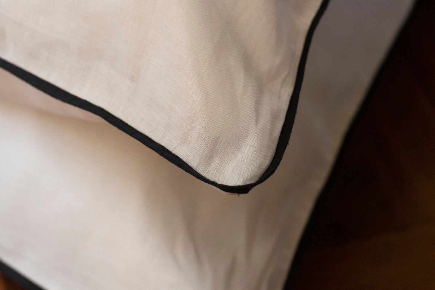 Close up of navy linen piping and white linen body. Corner of pillowcase image. 