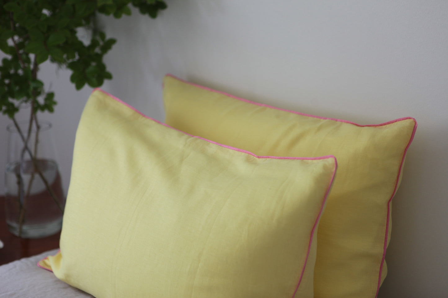 Lemon linen pillowcases with baby pink piping. Side studio photo. 