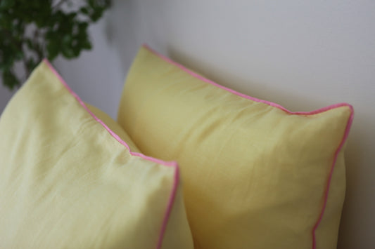 Lemon linen pillowcases with baby pink piping. 45 degree angle, shot from above. 